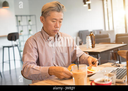 matured asian business male having breakfast Stock Photo