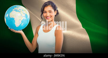 Pretty woman showing globe against digitally generated nigerian national flag Stock Photo