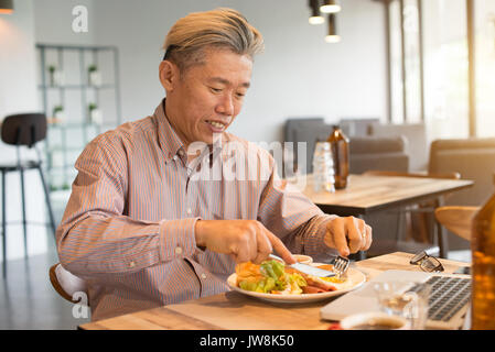 matured asian business male having breakfast Stock Photo