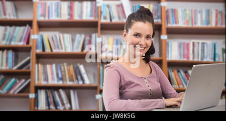Student on laptop against low angle view of various books on shelf Stock Photo