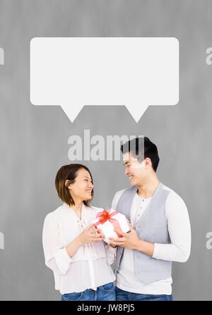 Digital composite of Couple with speech bubble smiling against grey background Stock Photo