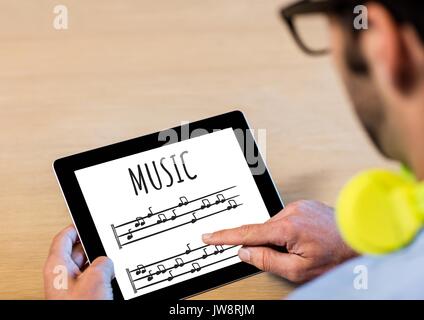Digital composite of Music notes on tablet screen with mans hands and earphones Stock Photo
