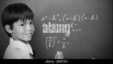 Digital composite of Boy writing math equations on blackboard Stock Photo