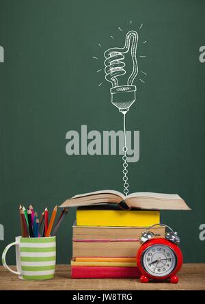 Digital composite of Books on the table against green blackboard with education and school graphics Stock Photo