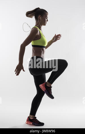 Desaturated back lit silhouette of athletic woman runner motion while  sprinting fast over gray studio background Stock Photo - Alamy