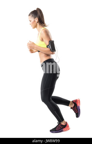 Relaxed young fit woman jogger jogging and looking down. Side view. Full body length portrait isolated on white studio background Stock Photo