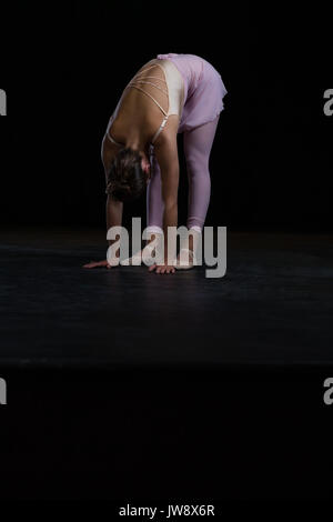 Ballerina performing stretching exercise in the stage Stock Photo