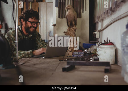 Smiling craftsman using laptop in workshop Stock Photo