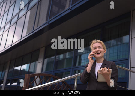 Smiling university student talking on mobile phone in campus Stock Photo