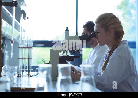 University students doing experiment on microscope in laboratory at college Stock Photo