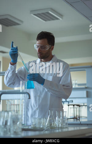 Attentive university student doing a chemical experiment in laboratory Stock Photo