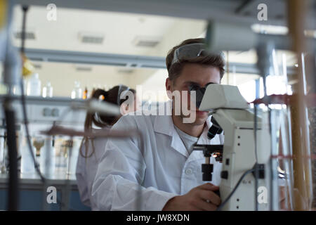Young male student using microscope in lab Stock Photo