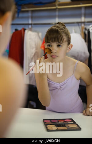 Close up of girl applying make up while reflecting in mirror Stock Photo
