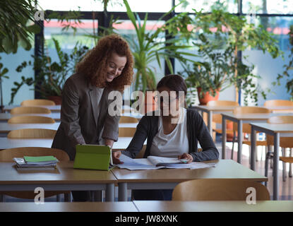 Smiling female students studying at desk in classroom Stock Photo