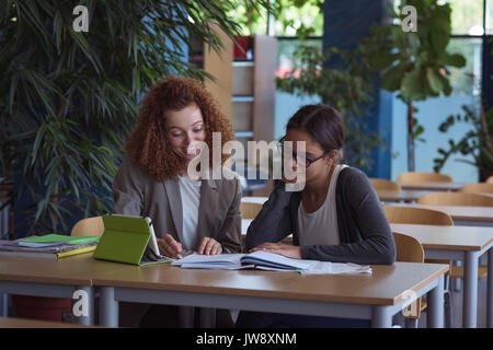 Smiling female university students studying at desk in classroom Stock Photo