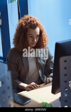 Female student using desktop computer while sitting at desk in classroom Stock Photo