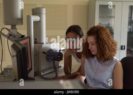 Female students using computer while practicing experiment in lab Stock Photo