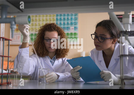 Female college students practicing chemistry experiment at desk in lab Stock Photo