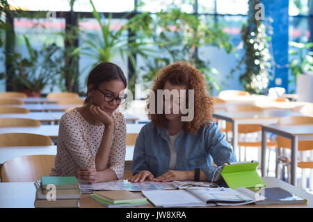 Female college students studying at desk in classroom Stock Photo