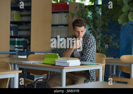 Young male university student studying at desk in classroom Stock Photo