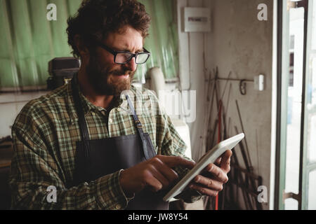 Attentive craftsman using digital tablet in workshop Stock Photo