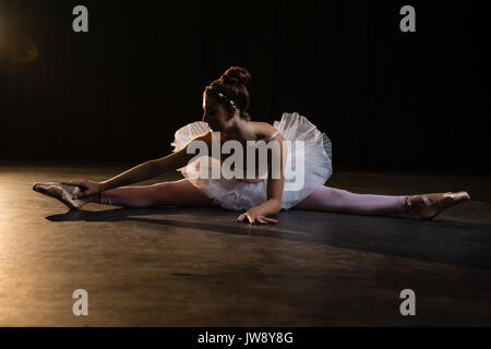 Female ballet dancer stretching before dancing in the studio Stock Photo