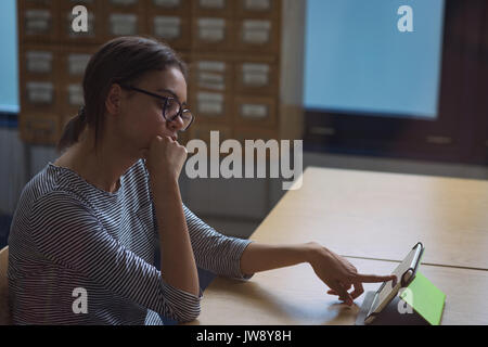 Teenage female student using digital tablet in desk in classroom Stock Photo