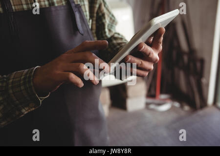 Mid-section of craftsman using digital tablet in workshop Stock Photo