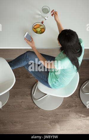 Top view of woman having breakfast while using mobile phone Stock Photo