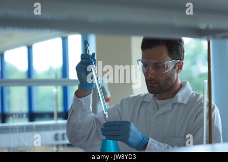 Attentive university student doing a chemical experiment in laboratory Stock Photo