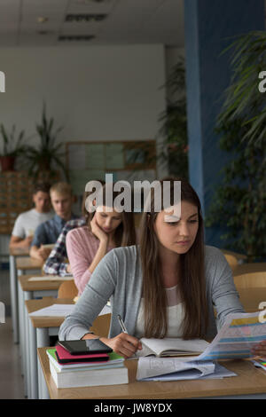 College students sitting at table during exam in classroom Stock Photo