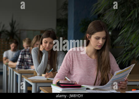 Unversity students sitting at table during exam in classroom Stock Photo