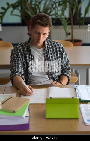 High angel view of young man using digital tablet while sitting at desk in classroom Stock Photo