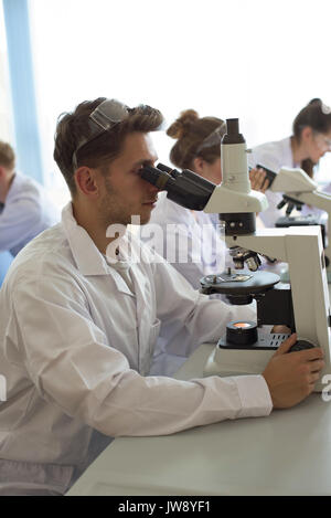 College students using microscope while practicing experiment in lab Stock Photo