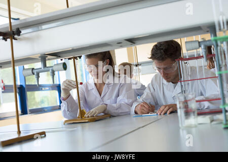 College students practicing chemistry experiment at desk in lab Stock Photo