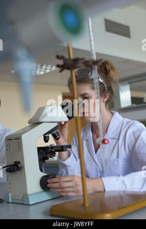 Young female student using microscope in lab Stock Photo