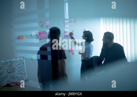 Colleagues discussing over sticky notes in office Stock Photo