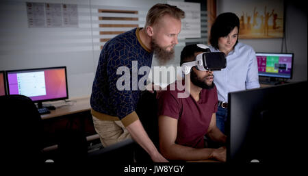Colleagues using virtual reality headset while working on computer in office Stock Photo