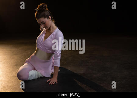 Female ballet dancer stretching before dancing in the studio Stock Photo