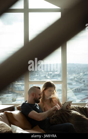 Romantic couple using digital tablet while lying on sofa at home Stock Photo
