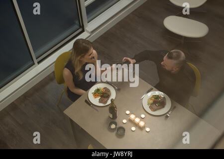 Couple toasting glass of wine while having dinner in living room at home Stock Photo