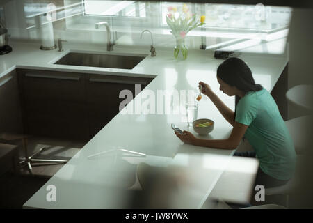 Woman having breakfast in the kitchen at home Stock Photo