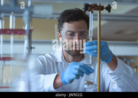 Attentive university student doing a chemical experiment in laboratory Stock Photo