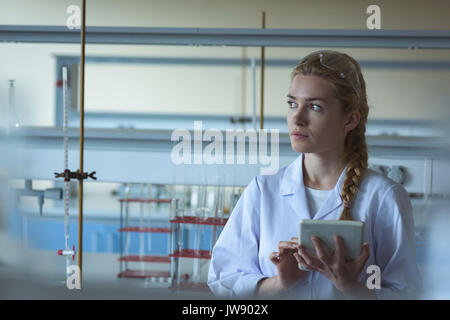 Thoughtful university student using digital tablet in laboratory Stock Photo