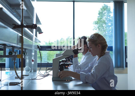 University students doing experiment on microscope in laboratory at college Stock Photo