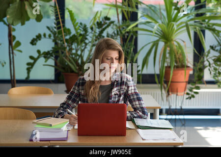 Young female student using laptop at desk in classroom Stock Photo