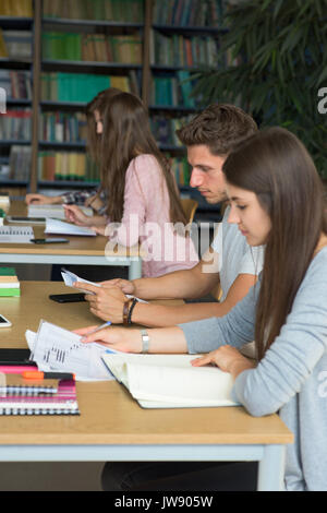 Side view of college students studying at desk in classroom Stock Photo