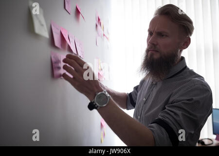 Attentive executive reading sticky notes in office Stock Photo
