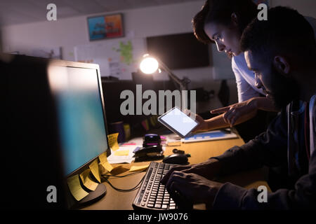 Colleagues using digital tablet while working at desk in office Stock Photo