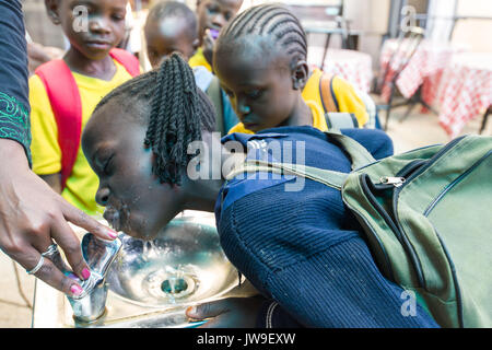Young school children from Kibera drinking from water fountain in Kibera Town Centre, Nairobi, Kenya Stock Photo